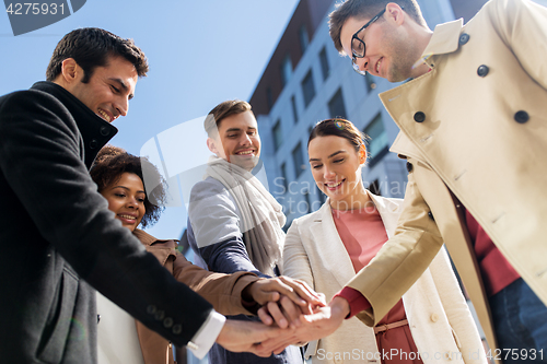 Image of group of happy people holding hands in city