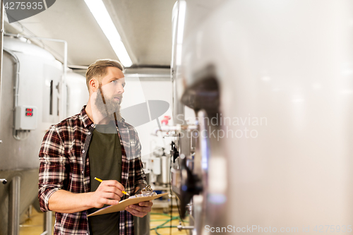 Image of man with clipboard at craft brewery or beer plant