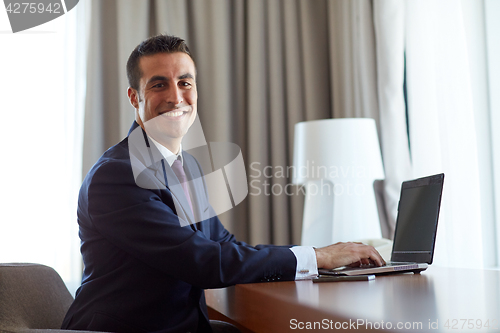 Image of businessman typing on laptop at hotel room