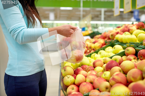 Image of woman with bag buying apples at grocery store