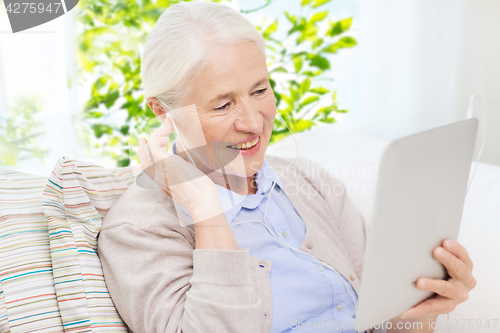 Image of senior woman with tablet pc and earphones at home