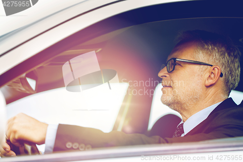 Image of happy senior businessman driving car