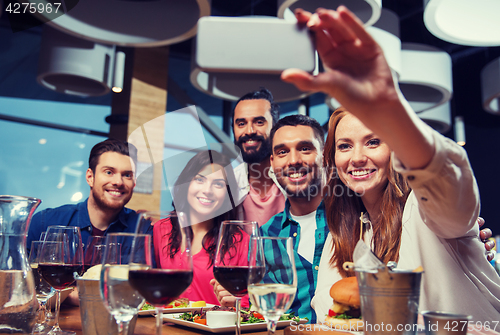 Image of friends taking selfie by smartphone at restaurant