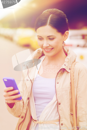 Image of smiling woman with smartphone over taxi in city