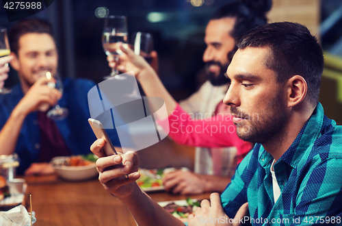 Image of man with smartphone and friends at restaurant