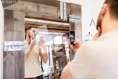 Image of man taking selfie by smartphone at barbershop