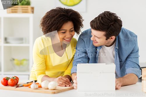 Image of happy couple with tablet pc cooking food at home