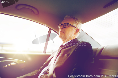 Image of senior businessman driving on car back seat
