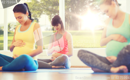 Image of happy pregnant women exercising yoga in gym