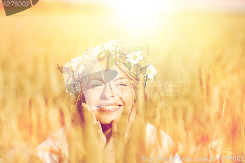 Image of happy woman in wreath of flowers on cereal field