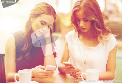 Image of women with smartphones and coffee at outdoor cafe