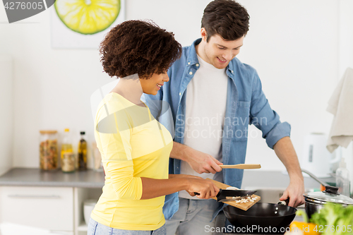 Image of happy couple cooking food at home kitchen