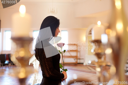 Image of sad woman with red rose at funeral in church