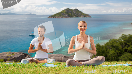 Image of happy couple doing yoga and meditating outdoors