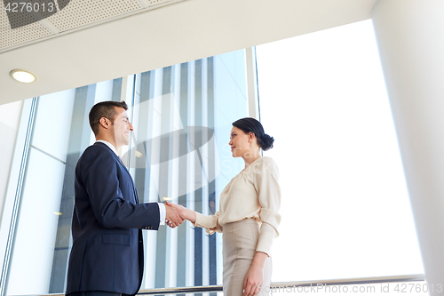 Image of smiling business people shaking hands at office