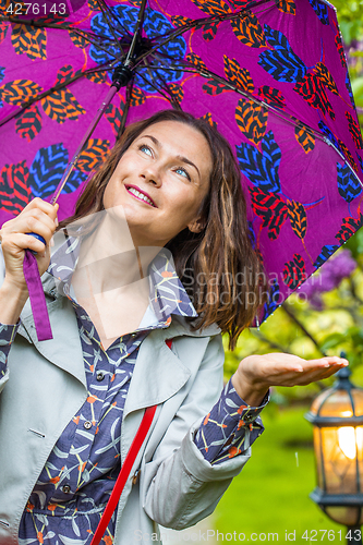 Image of Smiling woman with umbrella in the rain