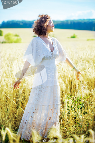 Image of happy smiling middle-aged woman spinning in a white dress in a f