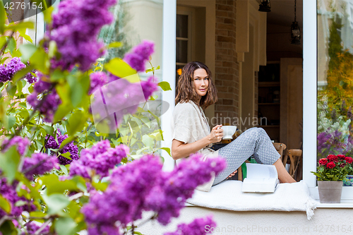 Image of Beautiful smiling middle-aged woman with a tea cup and a book