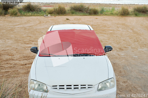 Image of Windshield of white car covered by piece of fabric