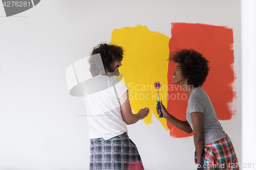 Image of multiethnic couple painting interior wall