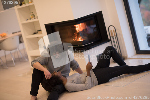 Image of multiethnic couple using tablet computer on the floor