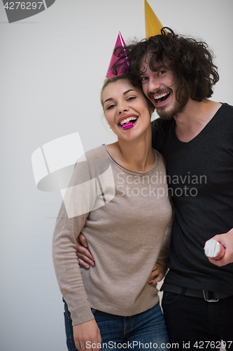 Image of couple in party hats blowing in whistle