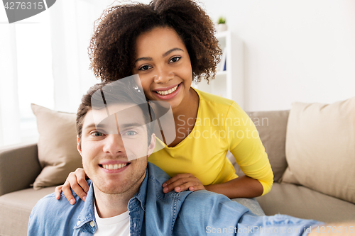 Image of happy multiethnic couple taking selfie at home