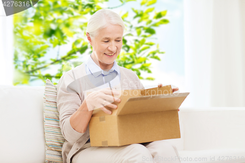 Image of happy senior woman with parcel box at home