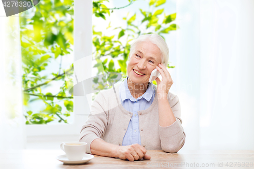 Image of senior woman with smartphone calling at home