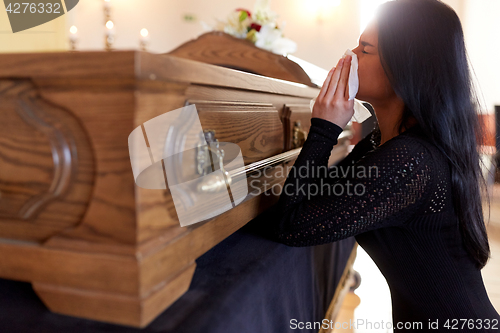 Image of woman with coffin crying at funeral in church
