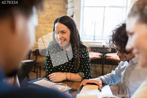 Image of happy friends looking to menu at restaurant