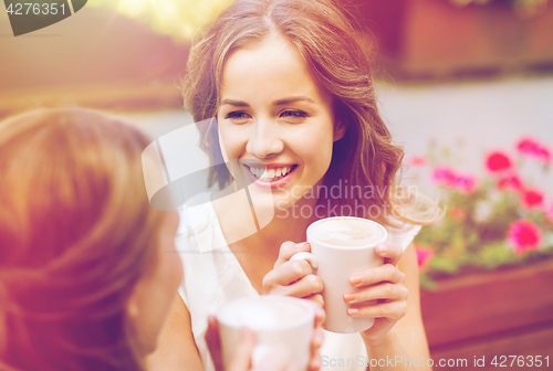 Image of smiling young women with coffee cups at cafe