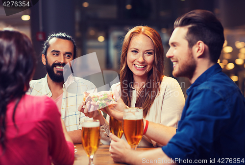 Image of friends eating pizza with beer at restaurant