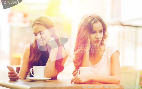 Image of women with smartphones and coffee at outdoor cafe