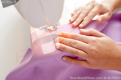 Image of tailor woman with sewing machine stitching fabric