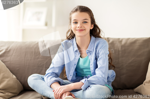 Image of happy smiling preteen girl sitting on sofa at home