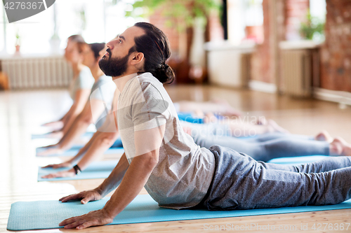 Image of group of people doing yoga cobra pose at studio