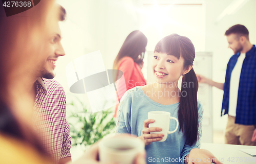 Image of happy creative team drinking coffee at office