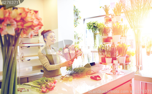 Image of smiling florist woman making bunch at flower shop