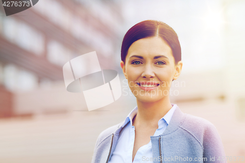 Image of young smiling businesswoman over office building