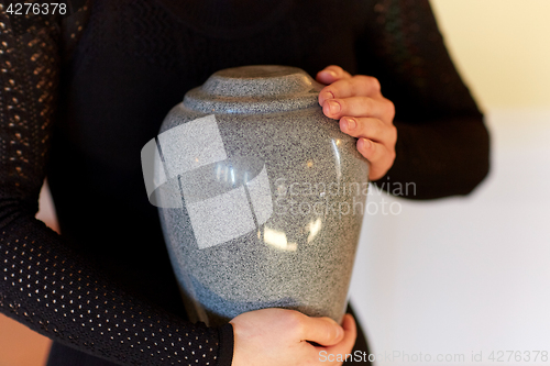 Image of close up of woman with cremation urn at funeral