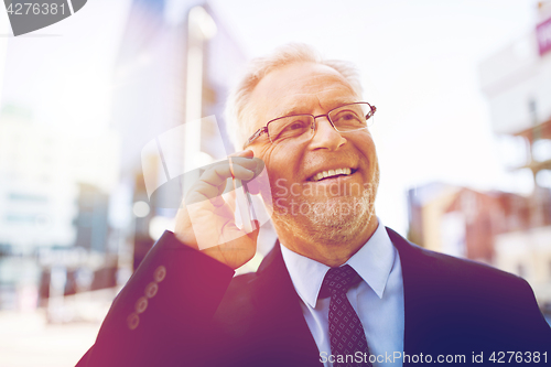 Image of smiling old businessman calling on smartphone