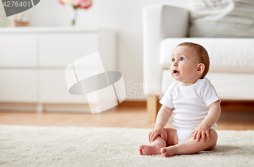 Image of happy baby boy or girl sitting on floor at home