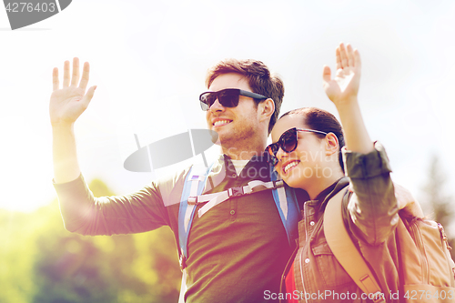 Image of happy couple with backpacks hiking outdoors