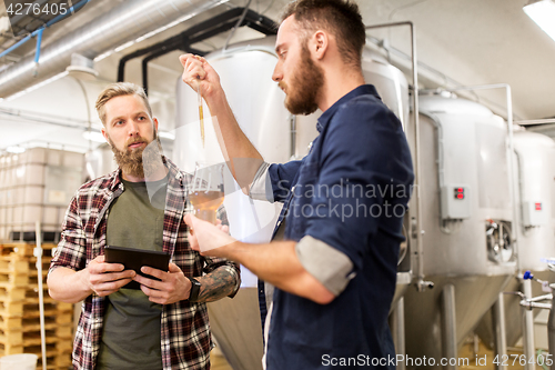 Image of men with pipette testing craft beer at brewery