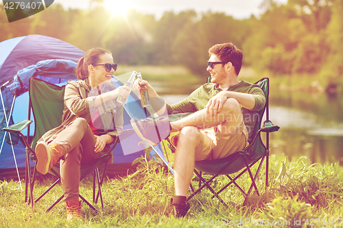 Image of happy couple clinking drinks at campsite tent