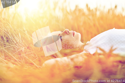 Image of young woman lying on cereal field and dreaming