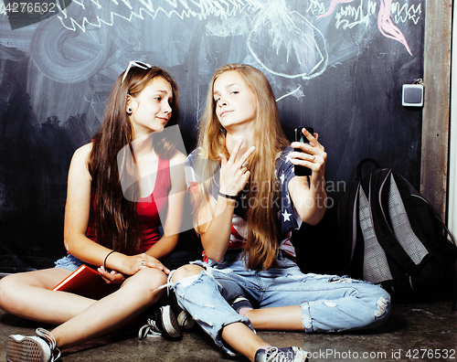 Image of back to school after summer vacations, two teen real girls in classroom with blackboard painted together, lifestyle people concept