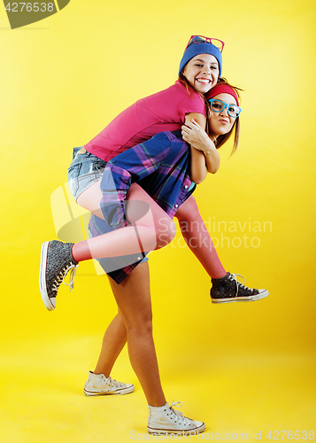 Image of lifestyle people concept: two pretty young school teenage girls having fun happy smiling on yellow background 
