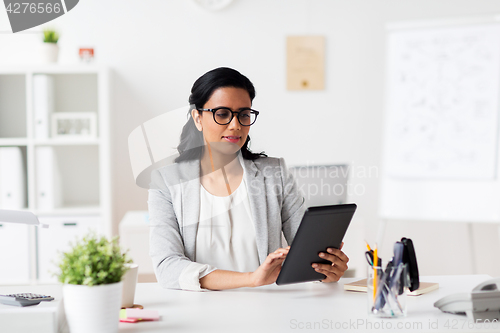 Image of smiling businesswoman with tablet pc at office